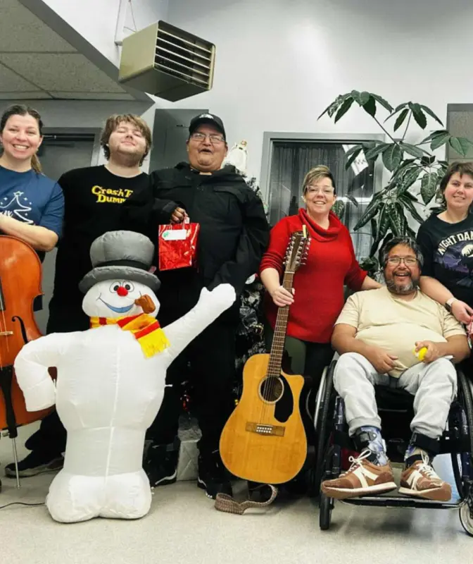 Group of Harmony Centre participants and staff celebrating together at a holiday event, with musical instruments and festive decorations.
