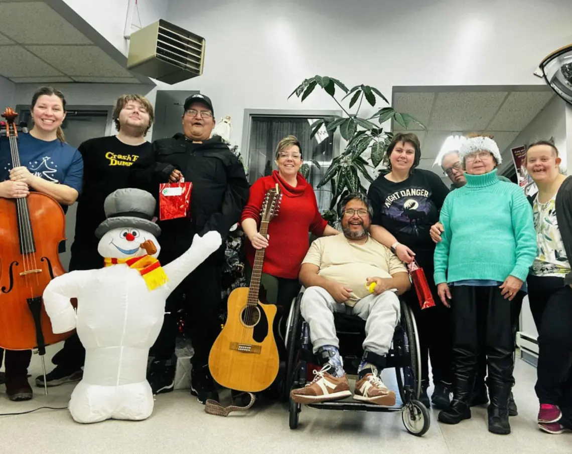 Group of Harmony Centre participants and staff celebrating together at a holiday event, with musical instruments and festive decorations.