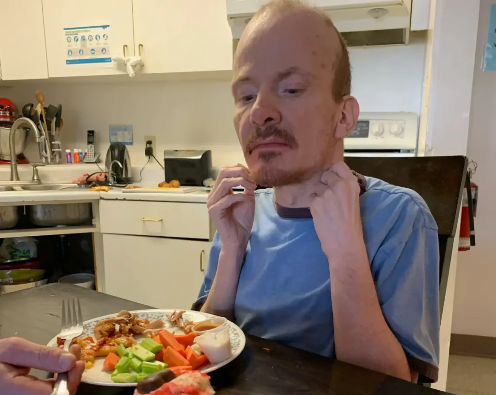 Harmony Centre participant enjoying a home-cooked meal at the kitchen table in a residential setting.